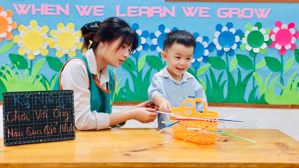 Cô giáo ngồi kèm riêng một bé bên bảng học